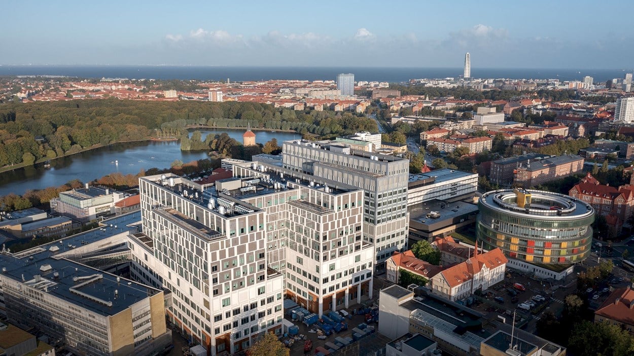 Drönarvy över sjukhusbyggnaderna med stadsvy i bakgrunden.