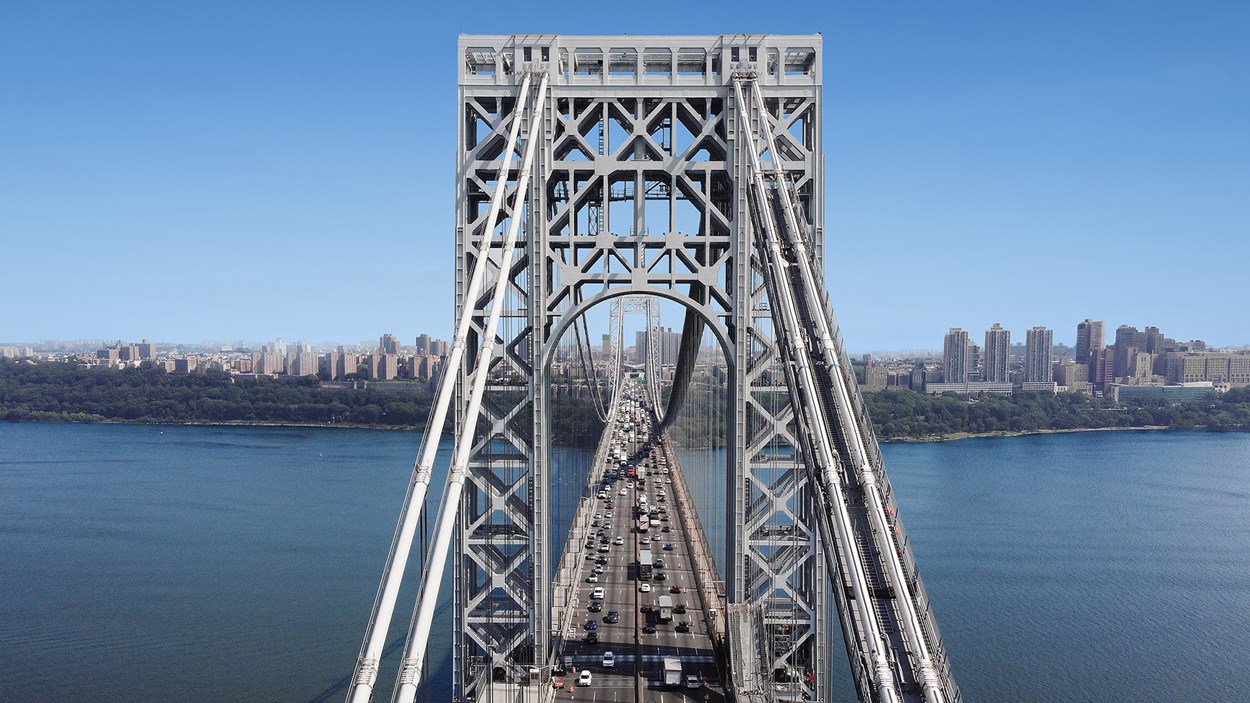 George Washingtonbron i New York hängbro i stål över vatten med skyline i bakgrunden.