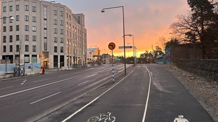 Arbetsplatsen omges av trafikerade vägar med bilar, bussar, gående och ett regionalt cykelstråk.