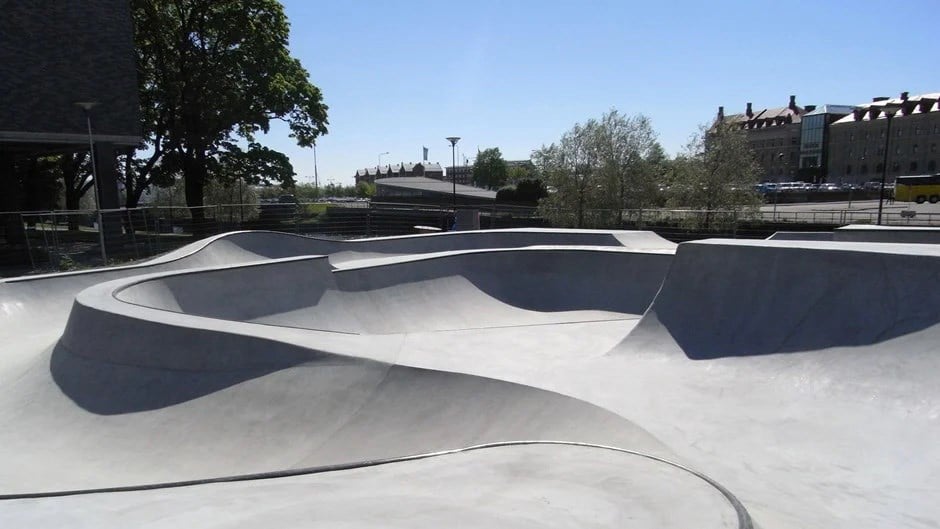 Skejtpark i grå betong med böljande runda former.
