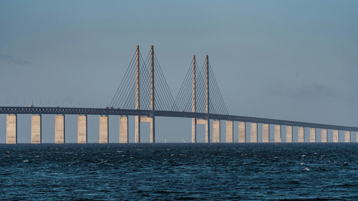 Bro äöver blått hav med fyra höga pyloner mitt på.